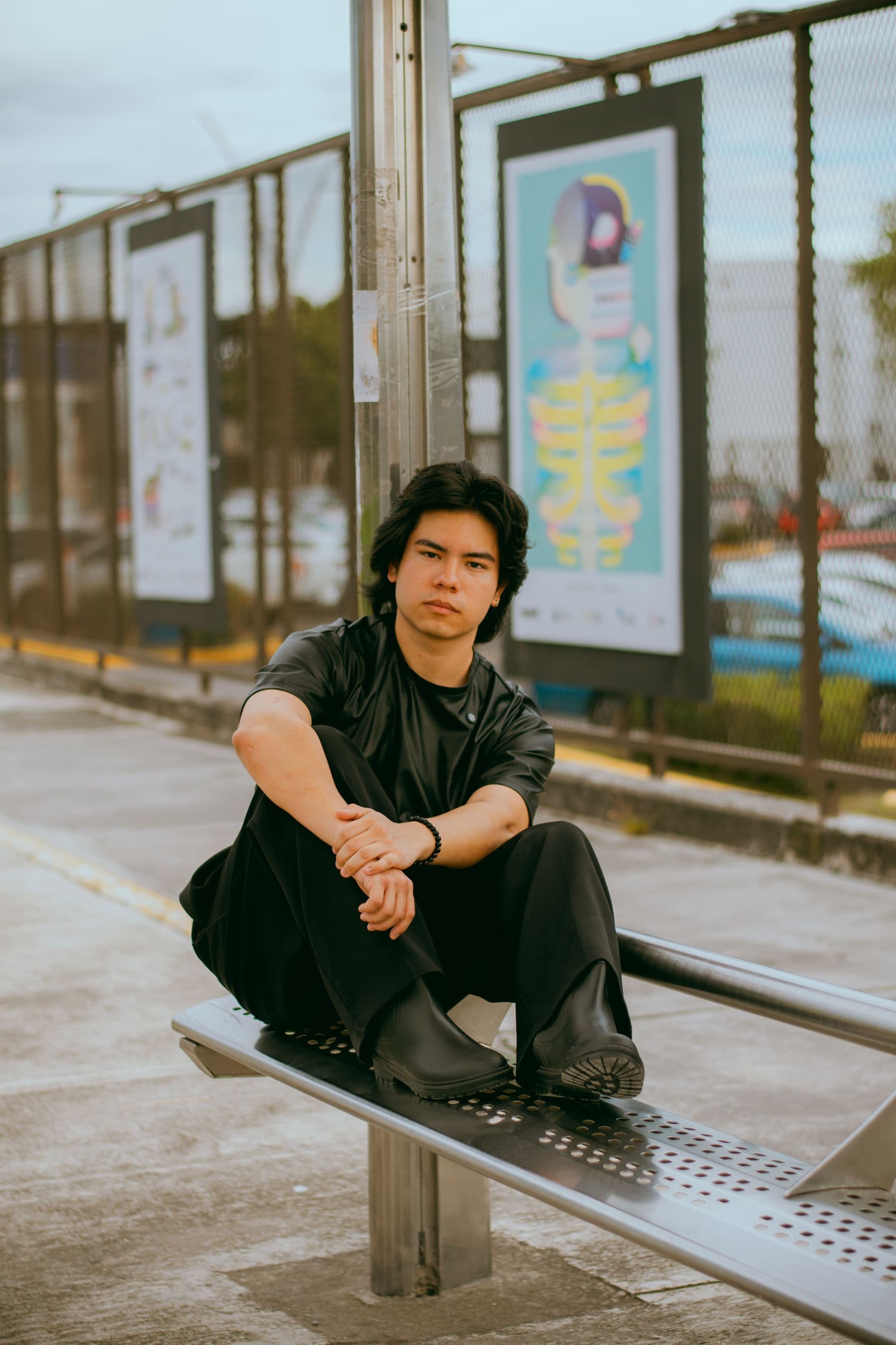 A young adult waiting alone at an urban bus stop